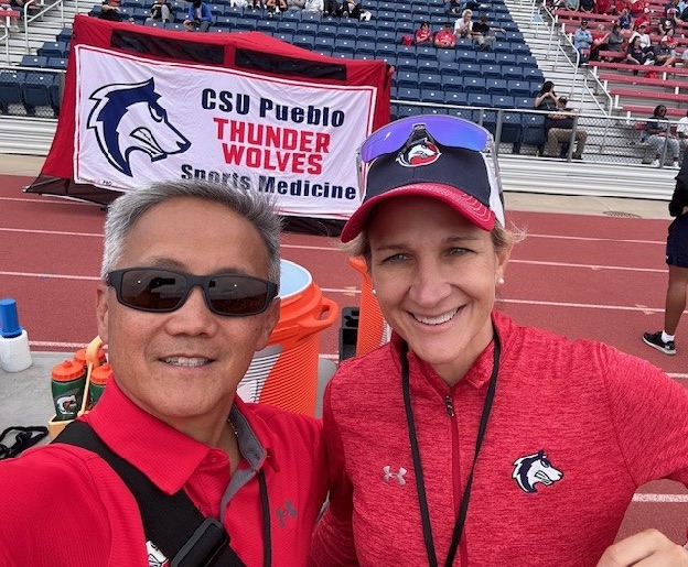Dr. FitzPatrick on the sideline in front of a CSU Pueblo Thunderwolves Sports Medicine banner