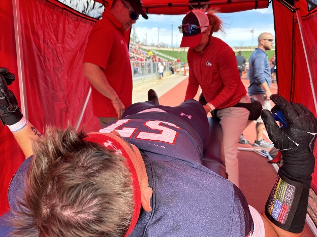 Dr. FitzPatrick's medical team treating an athlete in a tent beside a running track